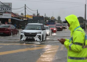 ANGGOTA trafik mengawal keadaan lalu lintas selepas Jalan Tunjong-Kota Bharu, Kelantan ditenggelami banjir. - UTUSAN/KAMARUL BISMI KAMARUZAMAN