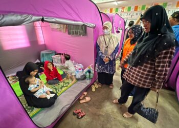 SITI Norina Muhamad (kanan) menyantuni  mangsa banjir di Pusat Pemindahan Sementara Sekolah Kebangsaan Pauh Sembilan, Bachok, Kelantan, semalam.