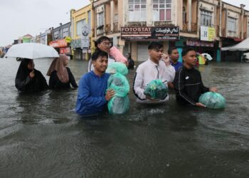 SEBAHAGIAN pelajar Universiti Malaysia Kelantan (UMK) meredah banjir selepas kawasan Kampus Kota di Pengkalan Chepa, Kelantan ditenggelami air sejak semalam. - UTUSAN/KAMARUL BISMI KAMARUZAMAN