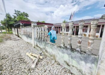 NOOR Azizah Mohd. Shari menunjukkan tembok pagar SRAR Madrasah Martaul Ulum di Tanjong Sari, Pasir Salak yang rosak dan perlu dibaiki, semalam. – MINGGUAN/AIN SAFRE BIDIN