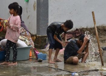 KANAK-KANAK menggunakan air lecak untuk membersihkan diri apabila kediaman mereka terputus bekalan air bersih susulan kejadian banjir dan tanah runtuh dekat Kampung Meunasah Blang, di Pidie Jaya, Aceh. – AIM