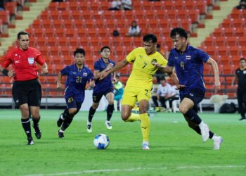 Pemain Thailand, Chanapach Buaphan (kanan) mengejar bola dari pemain Malaysia, Muhammad Haqimi Azim Rosli pada perlawanan bola Sukan SEA Thailand 2025 di Stadium Kebangsaan Rajamangala di sini hari ini. GAMBAR: FARIZ RUSADIO