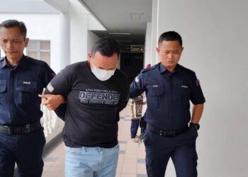 TERTUDUH yang diiringi anggota polis dihadapkan ke Mahkamah Majistret Ayer Keroh hari ini atas  pertuduhan mengugut teman wanita dan menyimpan gambar lucah. - UTUSAN/AMRAN ALI.