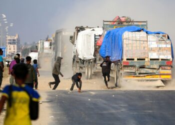 PENDUDUK Palestin mengejar trak bantuan yang melalui jalan Salah al-Din di tengah Gaza, berhampiran Deir al-Balah.- AFP