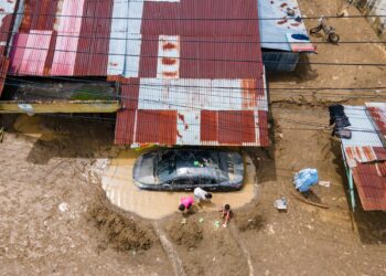 KANAK-KANAK bermain berhampiran sebuah kereta yang tersangkut dalam lumpur akibat banjir di Meureudu, di daerah Pidie Jaya, wilayah Aceh.- AFP