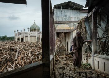 SEORANG pelajar berjalan di atas bangku untuk mengelak lumpur dan pokok tumbang di Sekolah Pondok Darul Mukhlisin di Aceh Tamiang, Sumatera Utara.-AFP