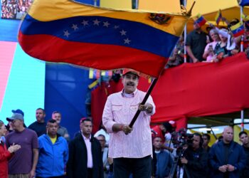 NICOLAS Maduro mengibarkan bendera Venezuela semasa perhimpunan di Caracas kelmarin. – AFP