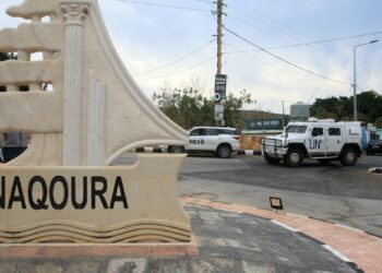 KENDERAAN PBB melalui papan tanda bandar Naqoura di kawasan selatan Lubnan berhampiran sempadan Israel.-AFP