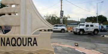 KENDERAAN PBB melalui papan tanda bandar Naqoura di kawasan selatan Lubnan berhampiran sempadan Israel.-AFP