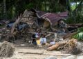 PENDUDUK kampung duduk di luar rumah mereka yang rosak akibat banjir kilat di Garoga, wilayah Sumatera Utara.- AFP