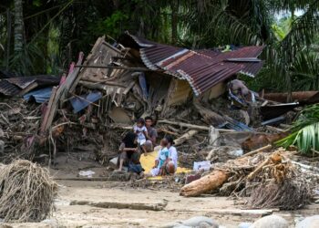 PENDUDUK kampung duduk di luar rumah mereka yang rosak akibat banjir kilat di Garoga, wilayah Sumatera Utara.- AFP