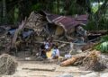 PENDUDUK kampung duduk di luar rumah mereka yang rosak akibat banjir kilat di Garoga, wilayah Sumatera Utara.- AFP