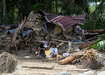 PENDUDUK kampung duduk di luar rumah mereka yang rosak akibat banjir kilat di Garoga, wilayah Sumatera Utara.- AFP