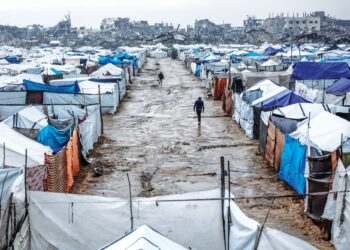 Penduduk berjalan di laluan berselut di khemah-khemah pelarian berdekatan daerah Zeitoun , Gaza selepas hujan lebat semalam. – AFP