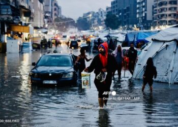 Penduduk Palestin yang tiada tempat tinggal berjalan meredah banjir berikutan hujan lebat di Gaza semalam. -AFP