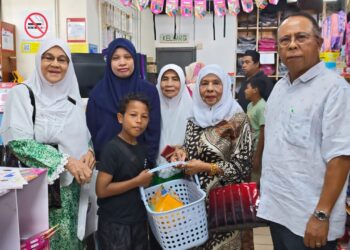 SITI Aishah Md. Lelah (dua dari kiri) bersama anak keduanya, Muhammad Iman Zafran, 10, menerima sumbangan kelengkapan sekolah daripada MDDNM di Bukit Serindit, Melaka. - UTUSAN/AMRAN ALI
