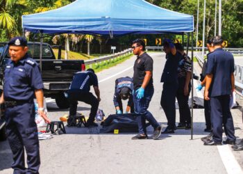 Anggota Forensik PDRM memeriksa mayatlelaki disyaki penjenayah yang ditembak mati dalam kejadian berbalas tembakan di Lebuh Raya Utara-Selatan di Bandar Darul Aman. – MINGGUAN/ SHAHIR NOORDIN