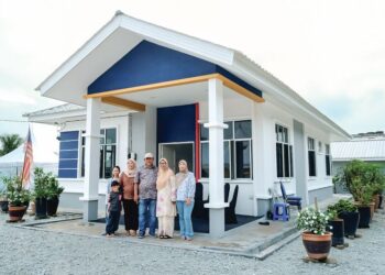 MOHD. Badly Nordin bersama ahli keluarganya di hadapan rumah yang baru mereka terima pada Majlis Penyerahan Kunci di Kampung Sungai Baru, Putra Heights, semalam. – UTUSAN/M. FIRDAUS M. JOHARI
