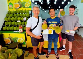 HENG Lai Lok bersama pelancong luar negara menunjukkan durian Musang King  di kedainya di Brinchang, Cameron Highlands, Pahang. – UTUSAN/AIN SAFRE BIDIN