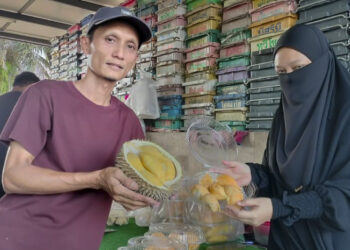 RAFAAIL Ismail dan bersama isterinya menunjukkan durian premium yang dijual dengan harga rendah 
di Parit Haji Ismail 3 di Bagan Serai, Perak. – UTUSAN/WAT KAMAL ABAS