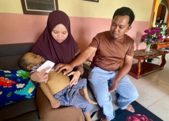 MUHAMMAD Arash Zulkarnain di samping ibu bapanya, Mohamad Fariz Najdi  dan Nor Syatirah ketika ditemui di Kampung Paya Sena, Pendang, Kedah semalam.