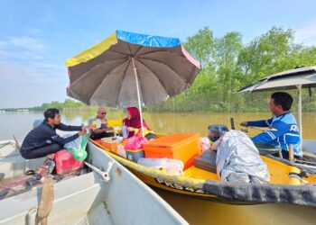 ZULKEFLI Md. Noor (dua dari kiri) dan Azian Jamal menjual makanan dan minuman kepada pemancing 
di tengah Sungai Perak di Teluk Intan, Perak. – UTUSAN/AIN SAFRE BIDIN