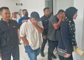 DUA tertuduh (tengah) dibawa keluar dari mahkamah selepas berdepan tuduhan menyalahgunakan jawatan bagi memperdaya seorang wanita untuk memberikan  wang sumbangan berjumlah RM800 di Mahkamah Seksyen Kangar, Perlis, hari ini.-UTUSAN/ASYRAF MUHAMMAD