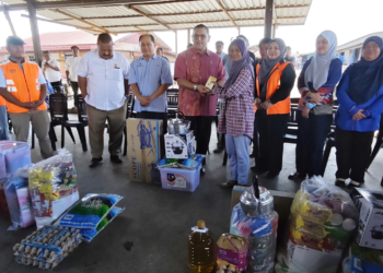 Nizam Abu Bakar Titingan (tengah) menyampaikan bantuan kepada wakil keluarga mangsa kebakaran di Kampung Sri Aman Batu 3, Tawau. - GAMBAR/BESSE AISYAH