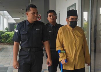 TERTUDUH diiringi anggota polis dihadapkan di Mahkamah Sesyen Ayer Keroh, Melaka atas tiga pertuduhan seksual membabitkan seorang remaja lelaki berusia 16 tahun pada Ogos tahun lalu.-UTUSAN/AMRAN ALI.