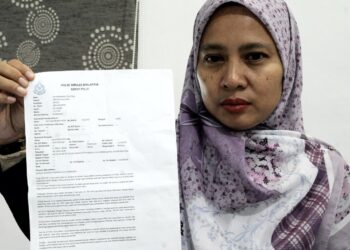 Elinoisna Abu menunjukkan laporan polis di rumahnya di Taman Setia Indah, Johor Bahru disini. UTUSAN/RAJA JAAFAR ALI