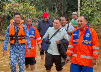 ANGGOTA APM Machang dan pembantu pegawai perubatan terpaksa meredah banjir sedalam 0.5 meter untuk membantu merawat pesakit strok di Kampung Temangan, Machang, Kelantan.-IHSAN APM.
