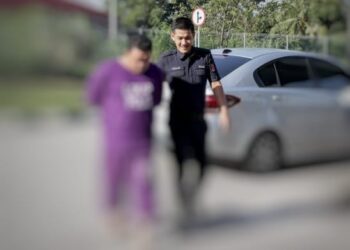 TERTUDUH dibawa oleh anggota polis untuk menghadiri prosiding perbicaraan di Mahkamah Sesyen, Kota Bharu, Kelantan hari ini-UTUSAN/KAMARUL BISMI KAMARUZAMAN.