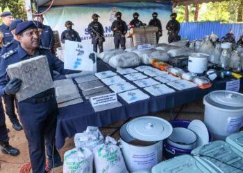 HUSSEIN Omar Khan (kiri) menunjukkan syabu yang telah dilarutkan ke dalam kepingan fabrik atau kanvas ketika sidang akhbar berkaitan rampasan dadah itu di sebuah kebun durian di Teluk Bahang, Pulau Pinang, hari ini.-UTUSAN/DANIAL SAAD