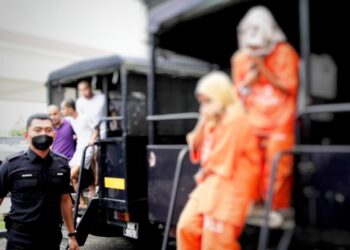 DUA beradik diiringi polis semasa hadir ke Mahkamah Kota Bharu, Kelantan untuk mendapatkan tempoh lanjutan reman hari ini-UTUSAN/KAMARUL BISMI KAMARUZAMAN.