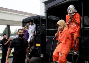 DUA beradik diiringi polis semasa hadir ke Mahkamah Kota Bharu, Kelantan untuk mendapatkan tempoh lanjutan reman hari ini-UTUSAN/KAMARUL BISMI KAMARUZAMAN.