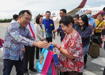 LOH Sze Yee (kiri) menyambut ketibaan penumpang yang menaiki penerbangan sulung Batik Air dari Singapura ke Ipoh di Lapangan Terbang Sultan Azlan Shah Ipoh hari ini. - UTUSAN/MUHAMAD NAZREEN SYAH MUSTHAFA
