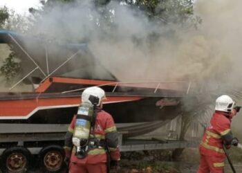 DUA anggota bomba cuba memadam kebakaran yang berpunca daripada sebuah bot di Bayan Lepas, Pulau Pinang hari ini.-GAMBAR/JBPM PULAU PINANG