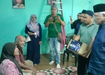 HAMZAH Zainudin (kanan) menyampaikan bantuan kotak makanan kepada penduduk di Kampung Sungai Angkat Ijok, Selama di Larut hari ini. - UTUSAN/WAT KAMAL ABAS