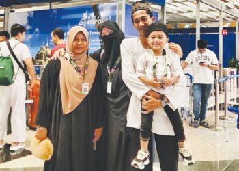PUTRI Qisya Nur Izzat Mohamad Azim (kiri) di samping keluarga Nur Adliah Syuhada Ishak sebelum berangkat menunaikan umrah di KLIA, semalam.
