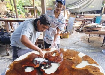 NAJIB Iskandar Mohamad (kiri) menyiapkan meja epoksi tempahan pelanggan di bengkelnya di Kampung Peragap Kuala Krau, Temerloh, Pahang.