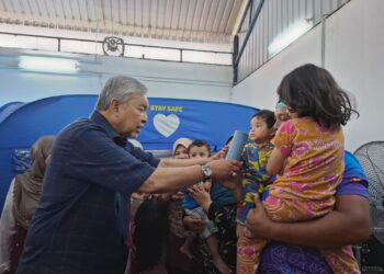 AHMAD Zahid Hamidi menyantuni mangsa banjir yang ditempatkan di PPS Dewan Pejabat Tanah dan Daerah Bagan Datuk, semalam.