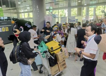 ANDI Md. Shamsureezal Mohd. Sainal menyambut ketibaan pelancong dalam dan luar negara di pintu masuk utama Lapangan Terbang Tawau, Sabah, semalam.-UTUSAN/BESSE AISYAH