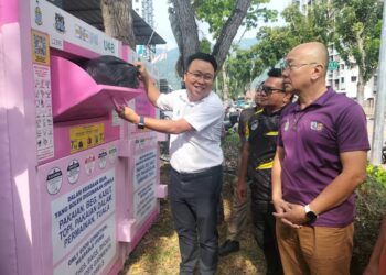 JOSEPH Ng Soon Siang (kiri) menunjukkan cara penggunaan tong kitar semula sisa tekstil di Taman Kejiranan Desa Mawar, Air Itam, Pulau Pinang.-UTUSAN/SAFINA RAMLI