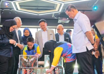 JAMES Ratib (kanan) menyaksikan sekumpulan pelajar yang menyertai program sempena pelancaran SainsXplor Tawau, Sabah haru ini. - UTUSAN/BESSE AISYAH