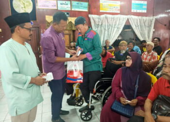 BAZLAN Abd. Rahman (tengah) menyampaikan sumbangan zakat kepada Asnan Othman (kanan) pada Majlis Penyerahan Zakat Ketengah Holdings peringkat Dewan Undangan Negeri (DUN) Batu Rakit, Kuala Terengganu.- UTUSAN/ERMA YUSNIDA JUSOH