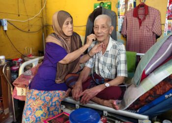 HANIM Azuar Mohamad membetulkan mesin oksigen yang dipakai suaminya, Mohd. Sapiee di rumahnya di Kampung Batu 17, Padang Rengas, Perak.