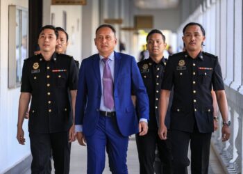 MOHAMED Fauzi Khamis diiringi pegawai Suruhanjaya Pencegahan Rasuah Malaysia hadir bagi menghadapi pertuduhan jenayah pecah amanah di Mahkamah Sesyen Kuala Lumpur, semalam. - UTUSAN/FARIZ RUSADIO