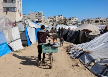 SEORANG lelaki membawa kanak-kanak menaiki basikal di kawasan khemah menempatkan keluarga Palestin yang terpaksa berpindah di Gaza City.-AFP