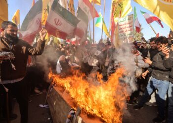 PENUNJUK perasaan membakar bendera Amerika Syarikat (AS) dan Israel semasa demonstrasi menentang ancaman ketenteraan Washington berhampiran kedutaan Iran di Baghdad.- AFP