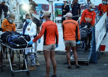 ANGGOTA Pengawal Pantai Filipina membawa beg mayat mangsa yang terkorban dalam insiden feri karam di Pelabuhan Manila, semalam.- AGENSI